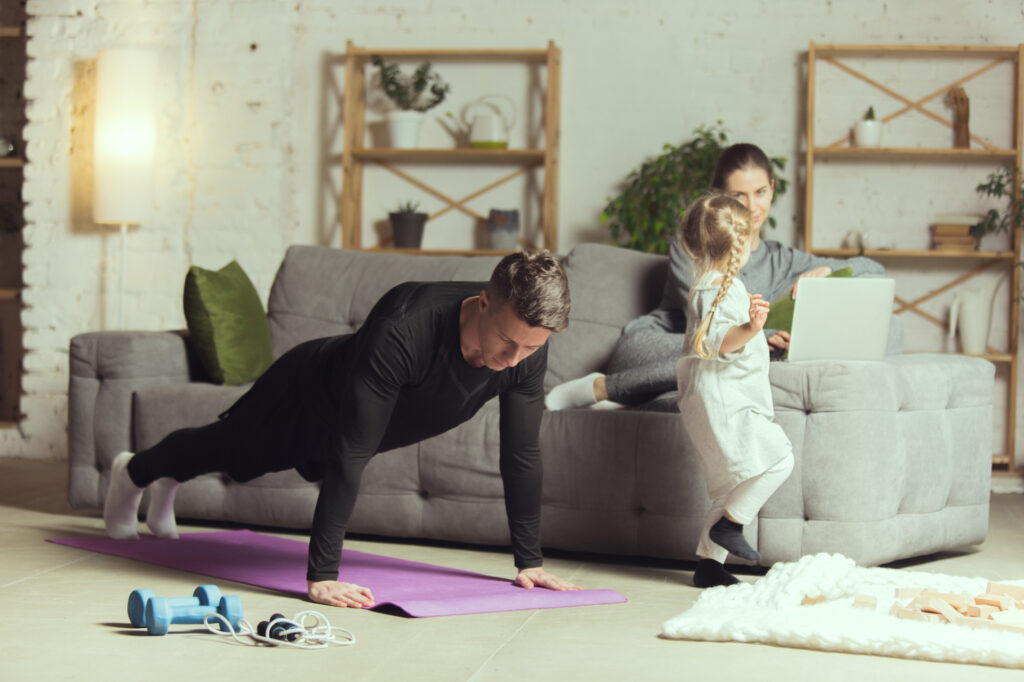 a man and a girl doing push ups in a living room